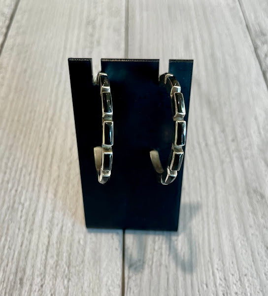 Half hoop sterling silver and black onyx post earrings displayed on a jewelry stand